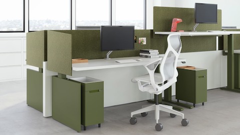 A workspace view featuring height-adjustable table workspaces with Ambit Workspace Solutions in olive color with a grey Cosm chair.