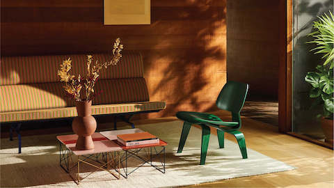 A sunny living room full of vibrant furnishings: a striped sofa, pastel coffee tables, and green side chair.