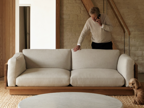John Pawson standing behind an ivory Pawson Drift Sofa in a living room with a dog. John Pawson standing behind an ivory Pawson Drift Sofa in a living room with a dog.