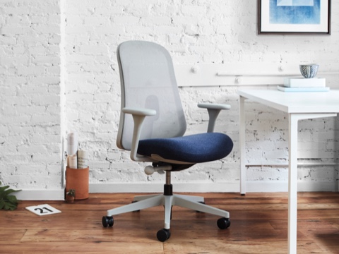 A mineral and blue Lino Chair viewed at an angle in front of a white Everywhere Table and white Ode Lamp in a brightly lit home office setting. A mineral and blue Lino Chair viewed at an angle in front of a white Everywhere Table and white Ode Lamp in a brightly lit home office setting.