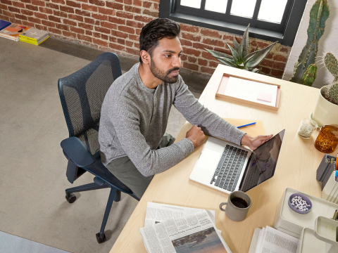 Man sits in the ergonomic Cosm Chair at his work desk, staring off past his laptop, lost in thought. Man sits in the ergonomic Cosm Chair at his work desk, staring off past his laptop, lost in thought.